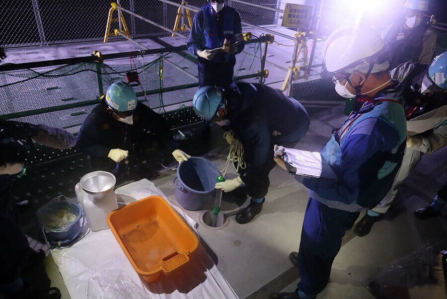 On Aug. 22, workers at the Fukushima Daiichi nuclear power plant check tritium levels in the contaminated water that has been diluted with sea water ahead of being released into the ocean starting on Aug. 24. (AFP/Yonhap)