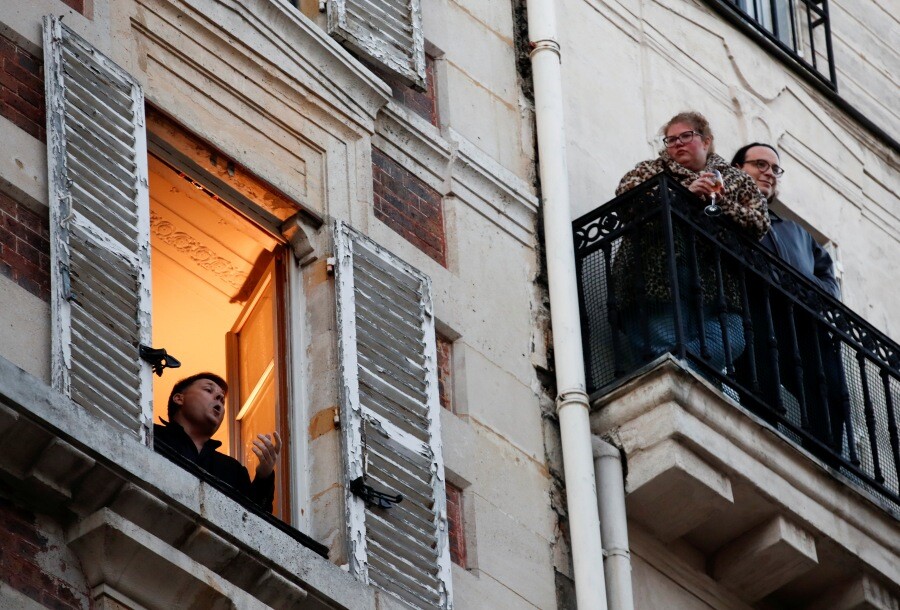 프랑스 테너 가수 스테판 세네샬이 3월24일 이동금지령이 내린 파리에서 자신의 아파트 창가에 서서 노래하는 동안 이웃 주민들이 발코니에 나와 이를 감상하고 있다.