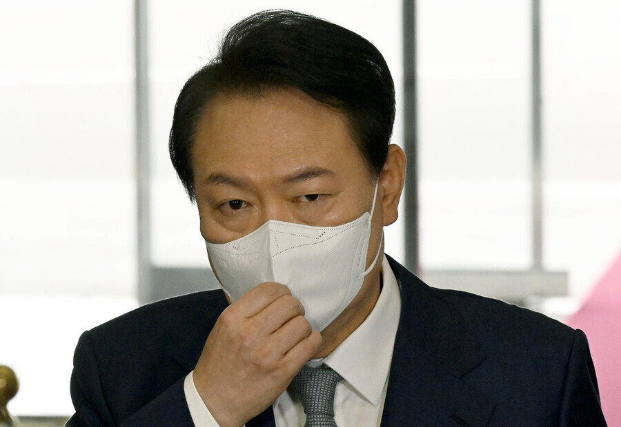 President Yoon Suk-yeol adjusts his mask while listening to questions from the press while heading into the presidential office in Yongsan, Seoul, on Oct. 6. (presidential office pool photo)