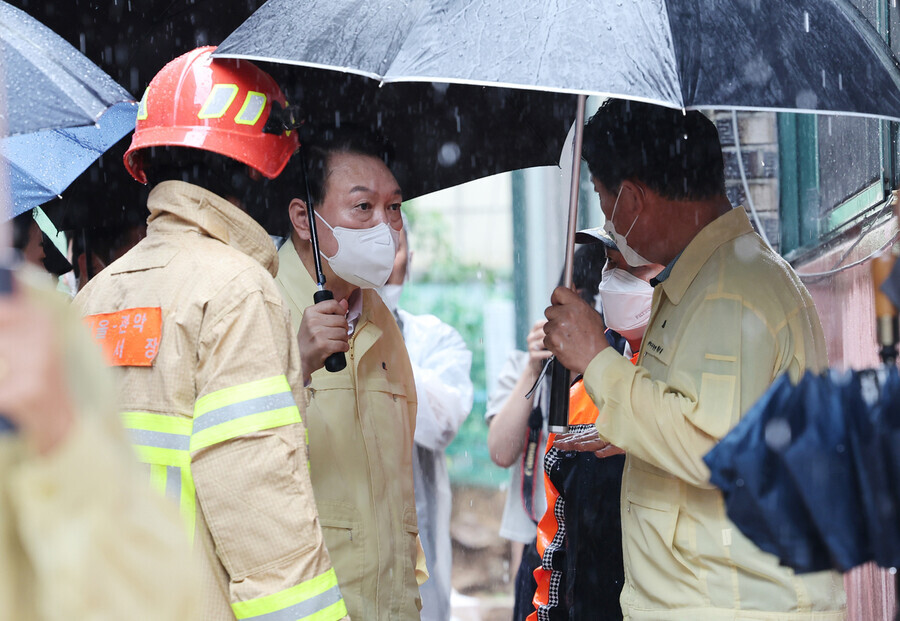 President Yoon Suk-yeol speaks to Park Jun-hee, the head of Gwanak District, outside the building where three members of the same family died during flash flooding on Aug. 8. (pool photo)