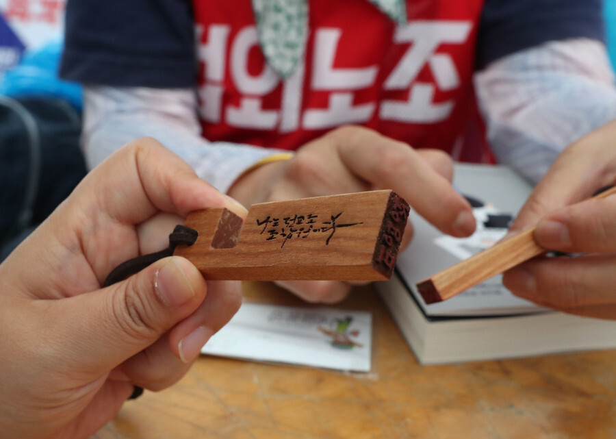 Terminated teachers view gifts of book-shaped stamps at a small park near Gwanghwamun Square on May 27, a day before the 30th anniversary of the Korean Teachers and Education Workers Union. (Baek So-ah, staff photographer)