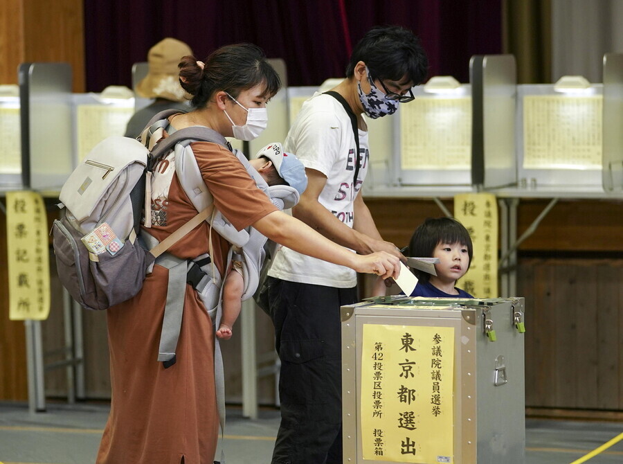 Japanese voters drop their ballots in the box at a polling station on July 10. (EPA/Yonhap News)