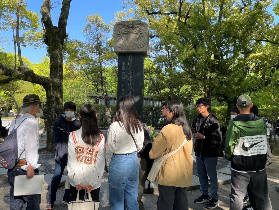 Visitors stand around a memorial stone for Korean victims of the atomic bombing of Hiroshima. Erected in 1970 by Korean victims of the bombing and Mindan, the stone was originally located outside of the park due to opposition from the city government. However, in May 1995 it was moved into the park, where it stands today. (Kim So-youn/The Hankyoreh)