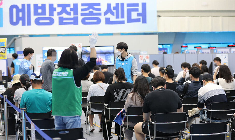At a COVID-19 vaccination center in Seoul on Monday, people sit and wait in a monitoring area after receiving their vaccine. (Yonhap News)