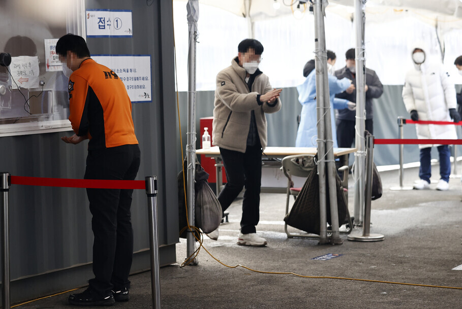 A line of people waiting to be tested for COVID-19 forms at a temporary screening station outside Seoul Station in central Seoul’s Jung District on Sunday. (Yonhap News)
