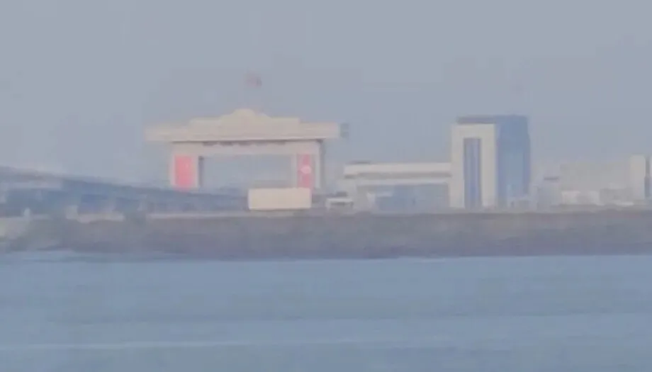 The flags of China and North Korea can be seen hanging on the customs facility on the North Korean side of the New Yalu River Bridge connecting Dandong in China's Liaoning Province, with Sinuiju in North Korea's North Pyongan Province on Oct. 13, 2026. (courtesy of a reader)