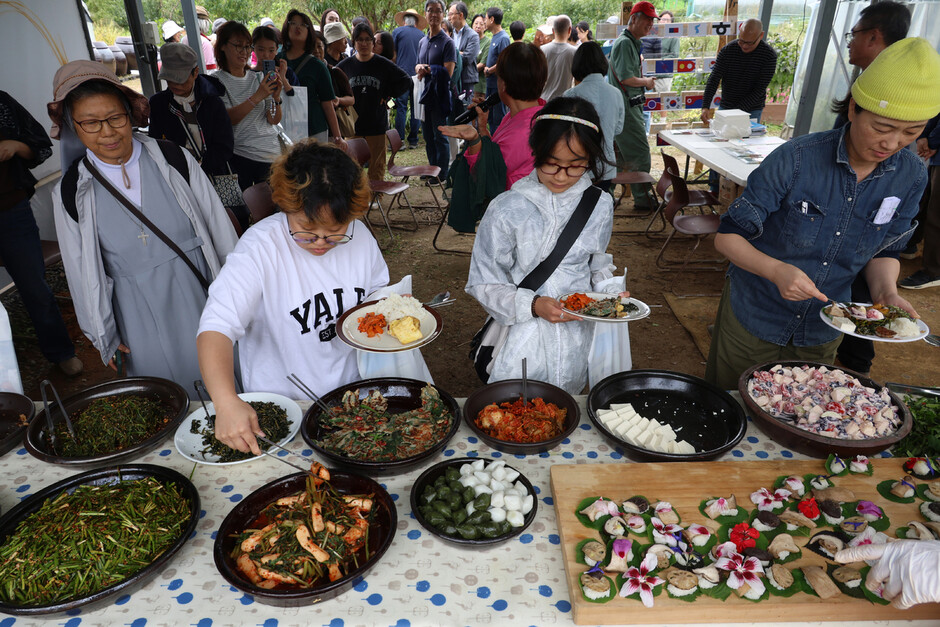평화마을짓자 가을잔치 참가자들이 공동체 밭에서 거둔 식재료 등으로 차린 ‘기후밥상' 음식을 접시에 담고 있다.