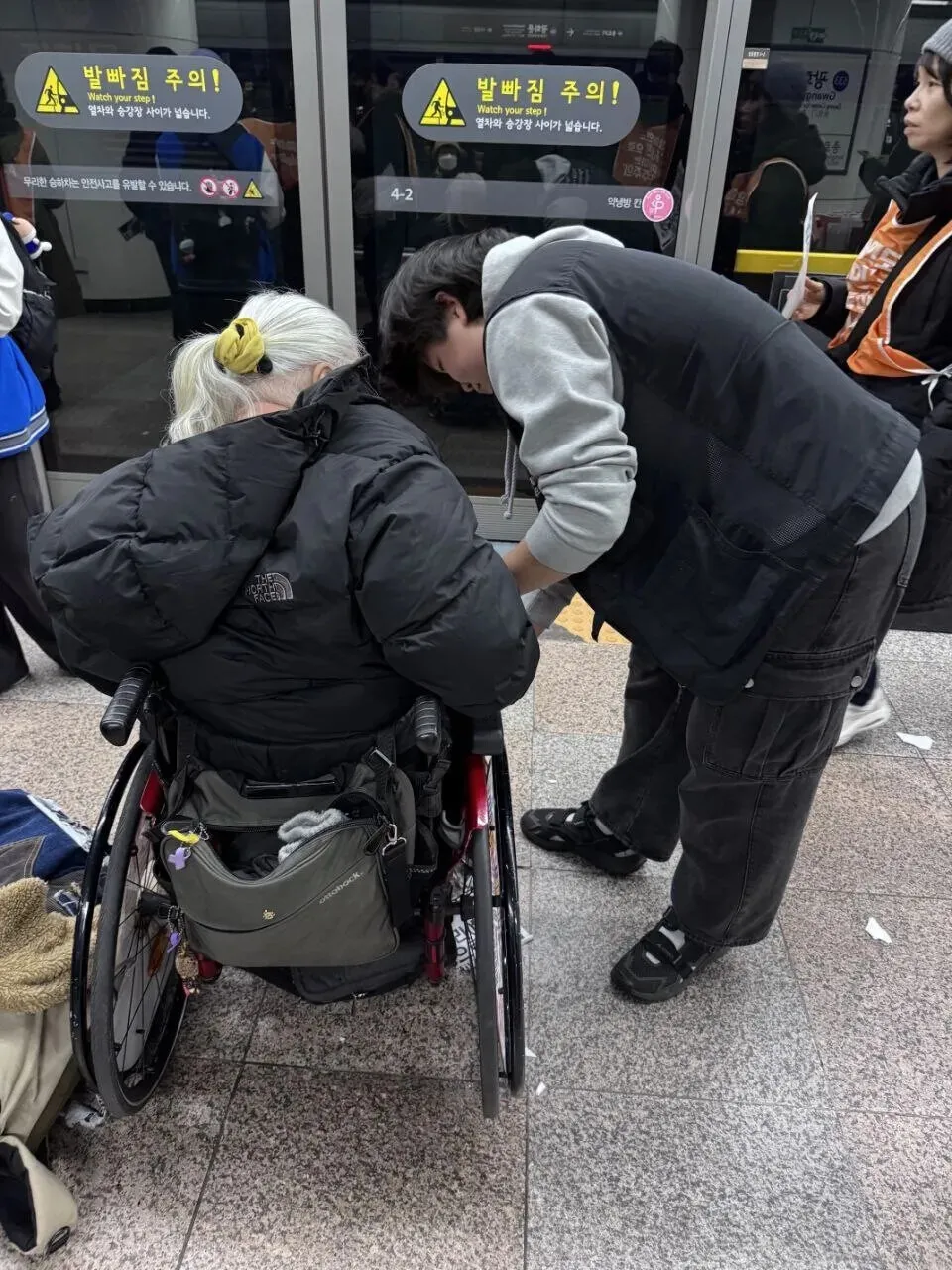 On Nov. 18, 2025, Moon Ga-bin works on the wheelchair of Park Kyung-seok, the leader of Solidarity Against Disability Discrimination, during the group’s 66th protest for mobility rights at the Gwanghwamun station on the Seoul metro. (Kim Hyo-sil/Hankyoreh)