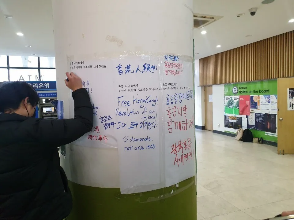 A student writes a message supporting the Hong Kong protests on a pillar in the student center of Yonsei University on Nov. 18.