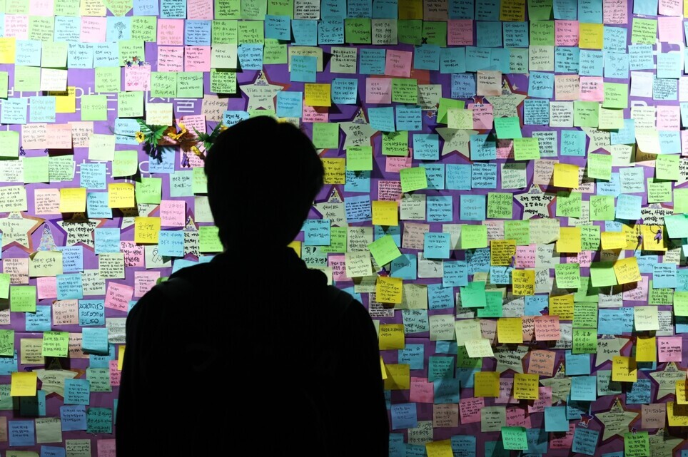 A person stands before a wall of the joint memorial altar for victims of the Oct. 29, 2022, crowd crush in Itaewon erected in Seoul Plaza for the first anniversary of the disaster. (Yonhap)