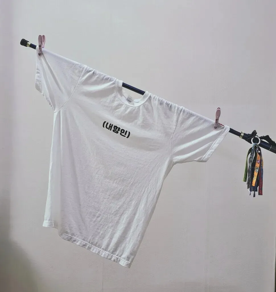 One of the most iconic flags at the rallies for Yoon’s impeachment was a white flag with only the text: “(introvert).” Kang Min-ji, who created and carried the flag, began producing and selling shirts with the same design in September as part of a fundraiser for a queer youth support center and food for rescue cats. (courtesy of Kang Min-ji)