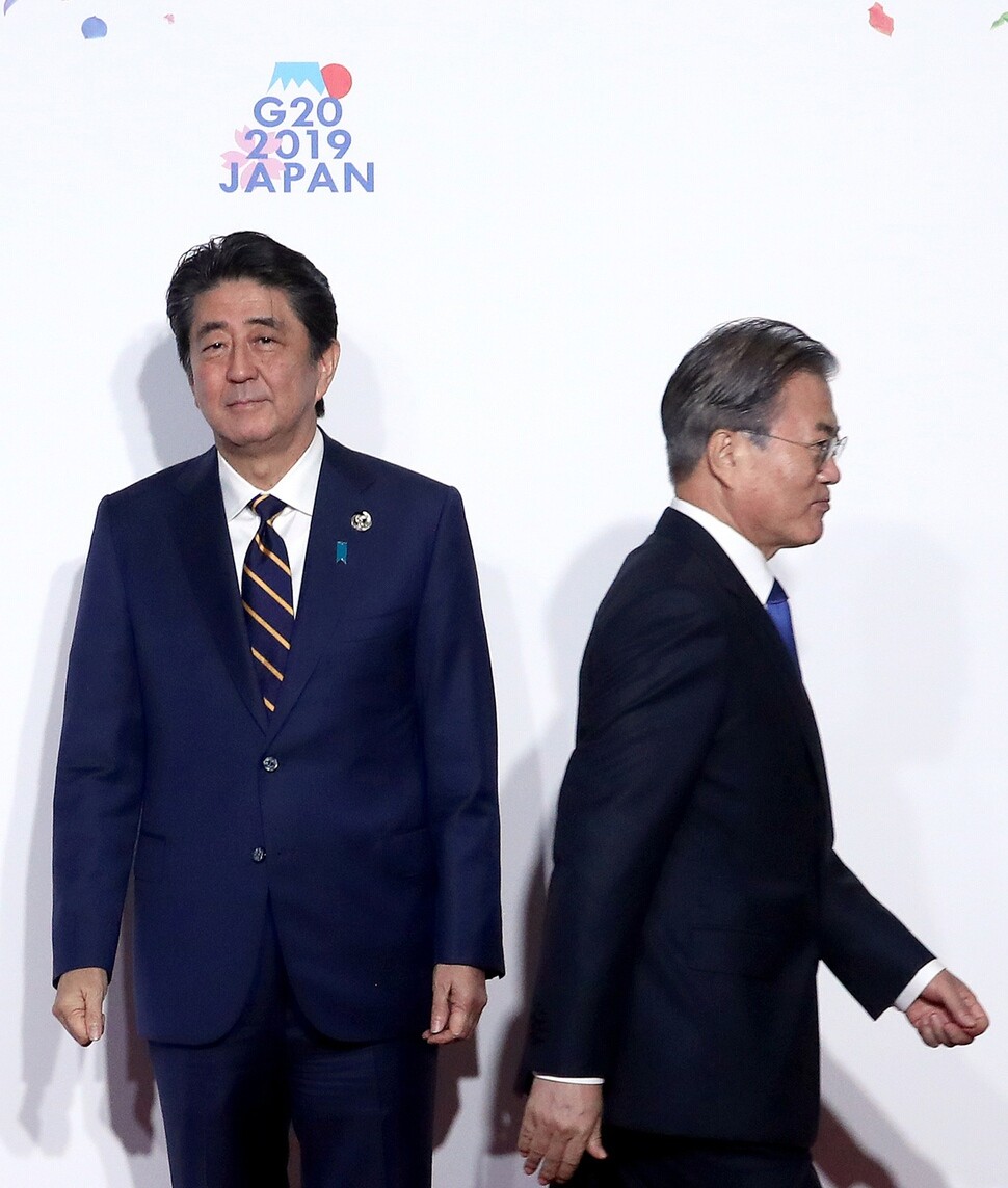 South Korean President Moon Jae-in walks away from Japanese Prime Minister Shinzo Abe after the two leaders briefly shake hands during the G20 Osaka summit on June 28. (Yonhap News)