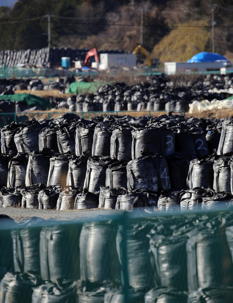 Big black plastic bags containing radiated soil, leaves and debris from the decontamination operation are dumped at a temporary site. (Yonhap News)