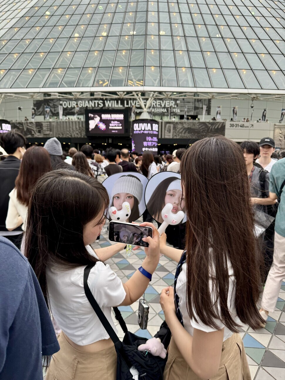 Fans snap pictures with NewJeans merch outside the Tokyo Dome before the “Bunnies Camp” fan meeting on June 27, 2024. (Suh Jung-min/Hankyoreh)