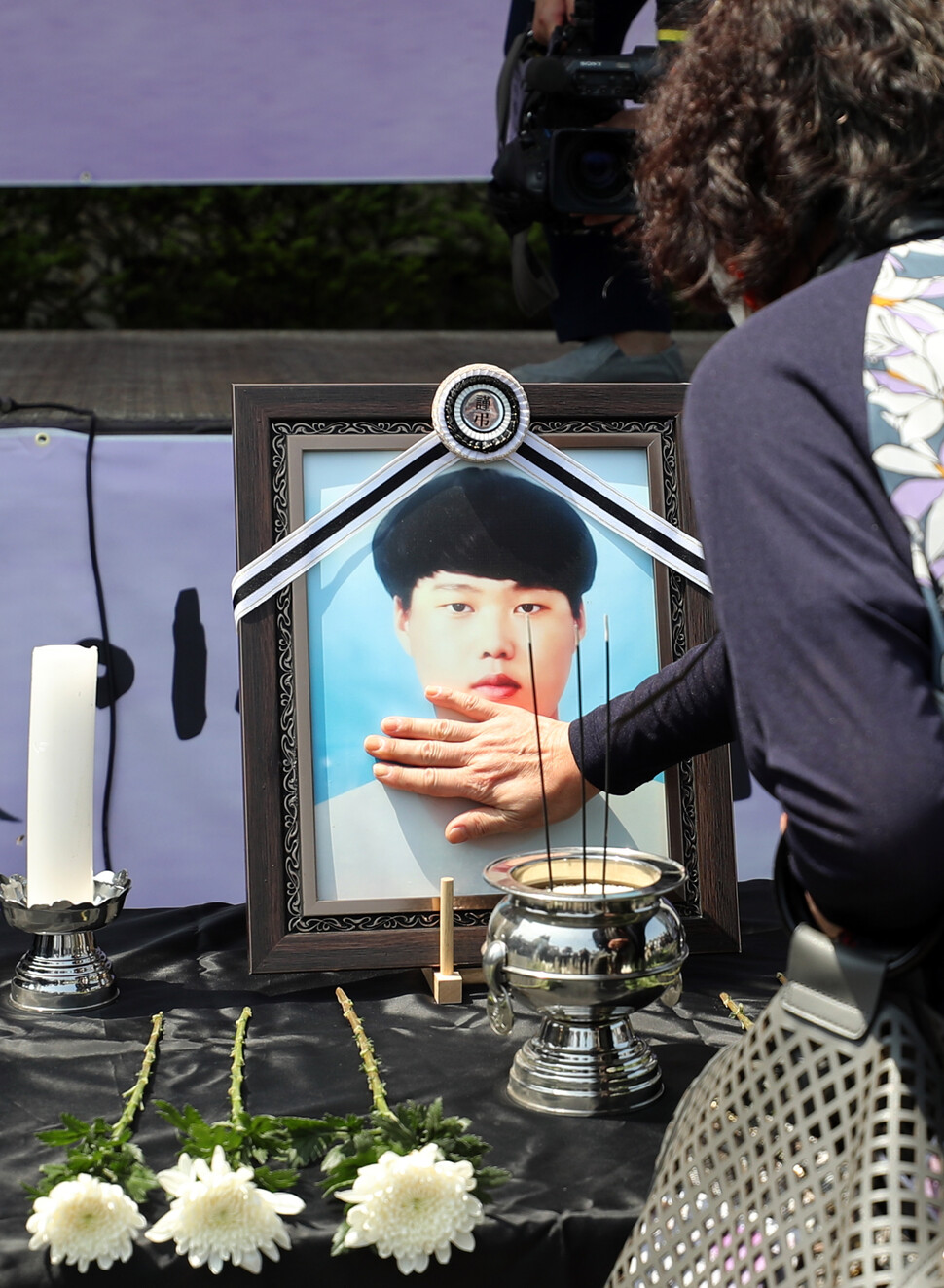 6월19일 평택시 안중백병원에서 열린 이선호씨 장례식에서 한 조문객이 이씨의 영정을 어루만지고 있다. 20대 청년인 이선호씨는 2021년 4월22일 평택항에서 일하다가 산업재해로 숨졌다. 연합뉴스