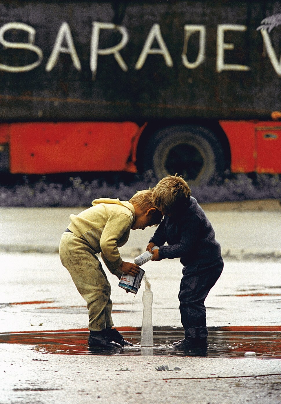 보스니아 어린이들이 1993년 8월29일 사라예보에 폭풍우가 지나간 뒤 웅덩이에서 물을 길어 병에 담고 있다.