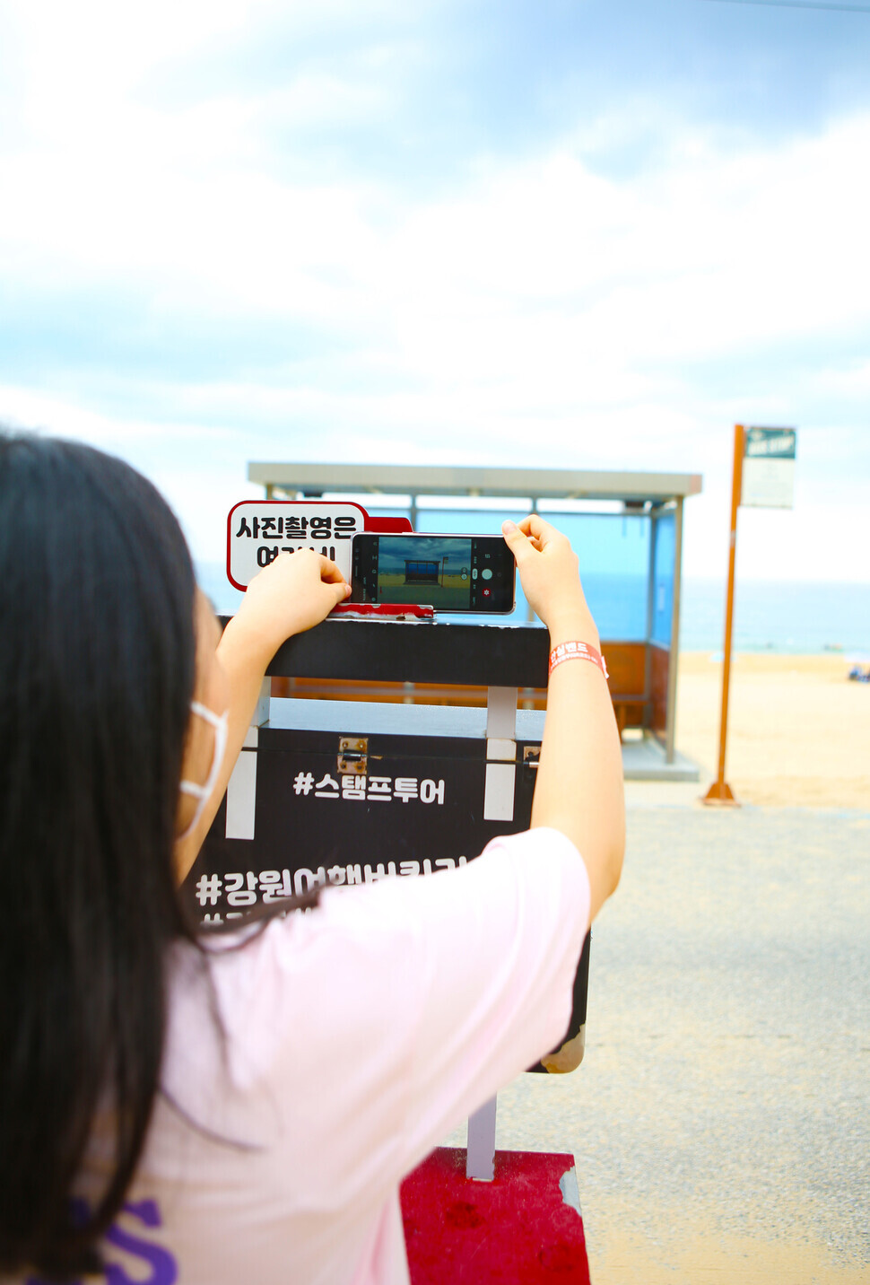 A traveler takes a photo of the “BTS bus stop” in Gangneung. (Her Yun-hee/The Hankyoreh)