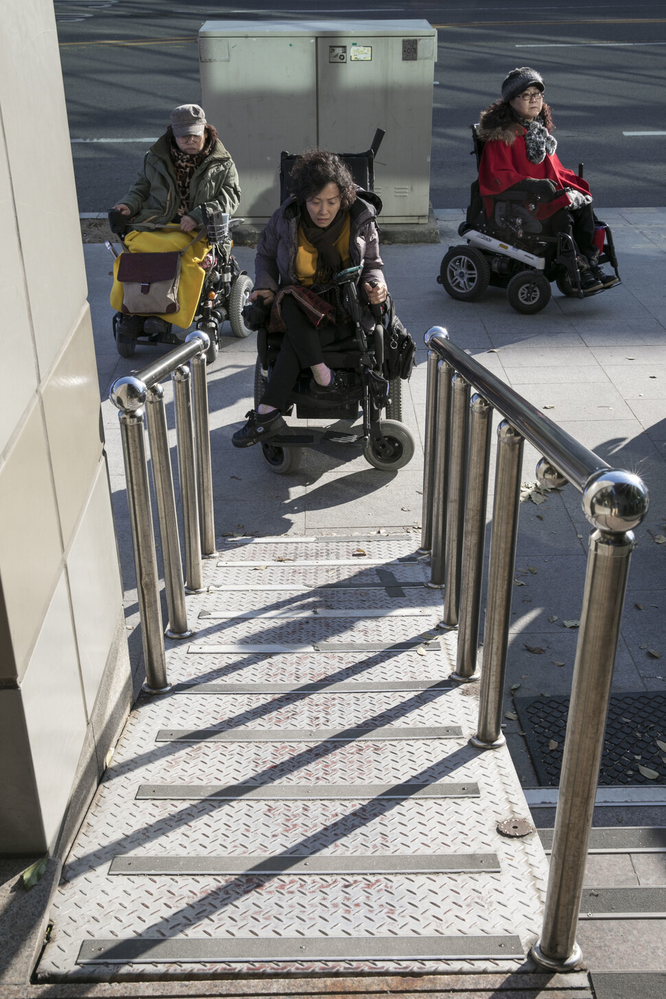 서울 양천구의 한 은행 출입구에서 휠체어를 탄 여성이 가파르게 설치된 경사로 앞에 있다. 한겨레 자료