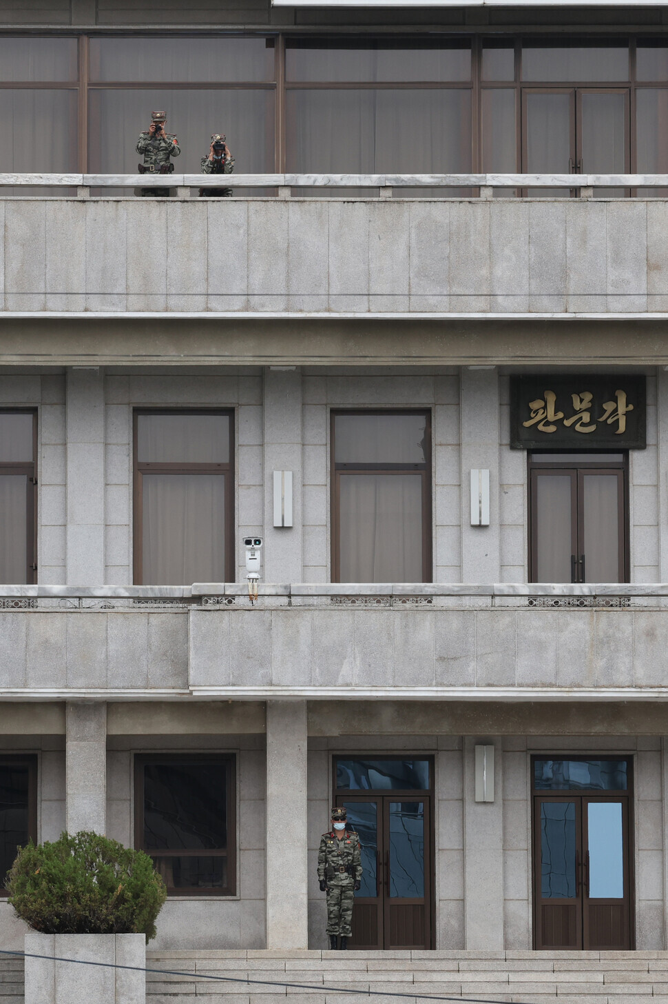 North Korean soldiers with a camera and binoculars peer over the balcony of Panmungak at the JSA. (Kim Hye-yun/The Hankyoreh)