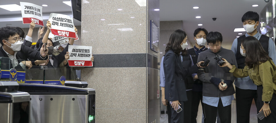 서울지하철 2호선 신당역 여자화장실에서 스토킹하던 20대 여성 역무원을 살해한 피의자 전주환이 2022년 9월21일 남대문경찰서에서 검찰로 이송되고 있다. 왼쪽은 피의자의 강력 처벌을 촉구하는 진보당 당원들. 공동취재사진