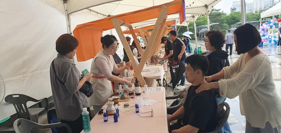 지난 6월25일, 경기도 광명시 하안동 광명시민체육관 야외광장에서 열린 ‘2025 광명새일 디딤돌 플리마켓’에서 권선옥씨(왼쪽 두번째)가 마사지 체험을 안내하고 있다. 권선옥씨 제공