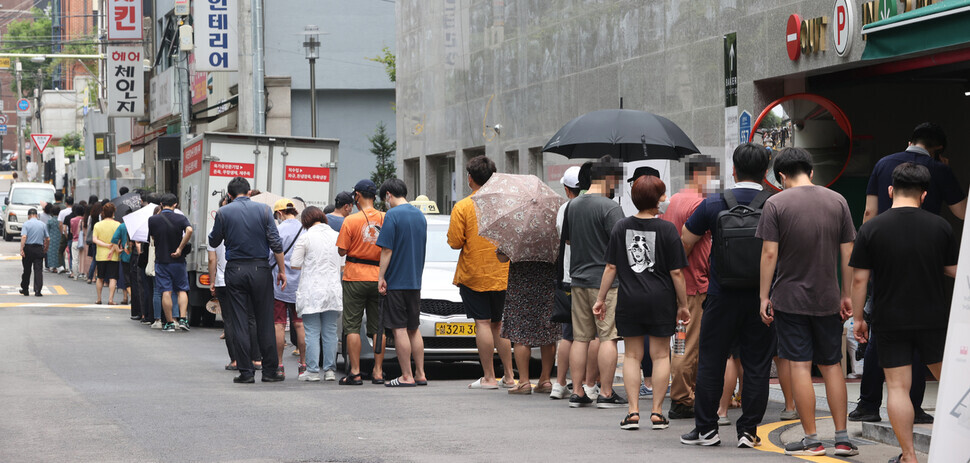 People wait in line at a temporary screening center in Seoul to get tested for COVID-19 on Sunday. (Yonhap News)