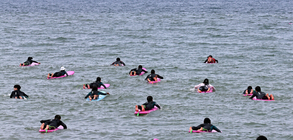 New surfers who have learned the basics head out into the water to catch some waves. (Lee Jeong-yong/The Hankyoreh)