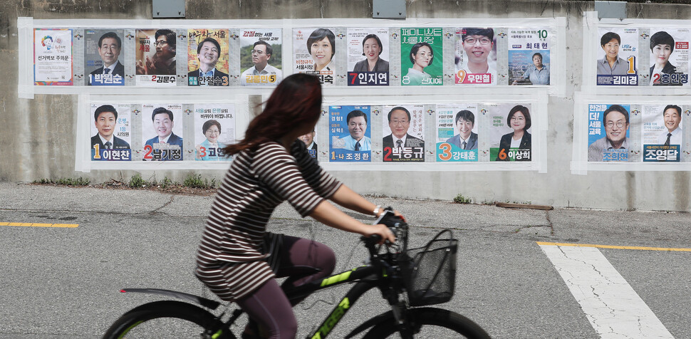 2018년 5월31일 서울 은평구의 한 시민이 자전거를 탄 채 제7회 전국동시지방선거에 출마한 후보자들의 모습이 담긴 벽보를 보며 지나가고 있다. 한겨레 신소영 기자