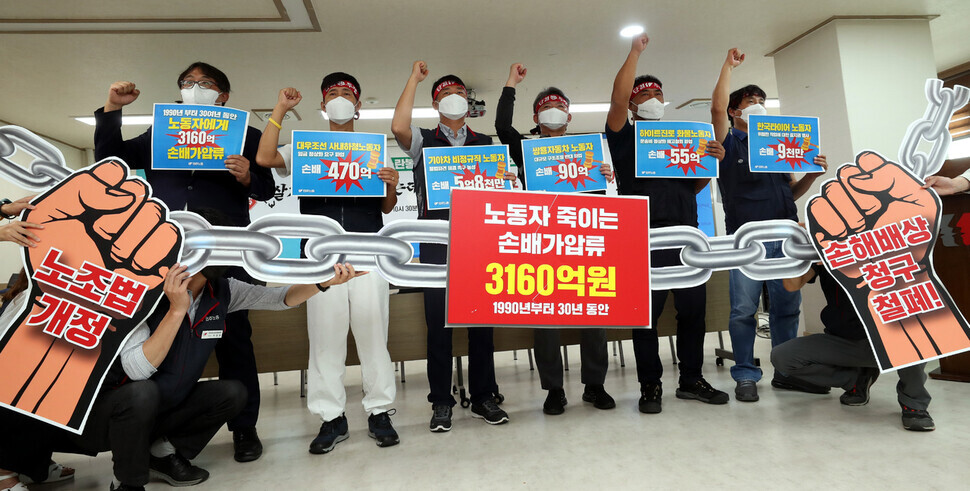 Laborers who have been sued by corporations for damages and provisional seizure over labor strikes hold up signs calling for the revision of the Trade Union Act and the repeal of damages claims during a press conference at the KCTU office space in downtown Seoul on Aug. 31. (Kang Chang-kwang/The Hankyoreh)