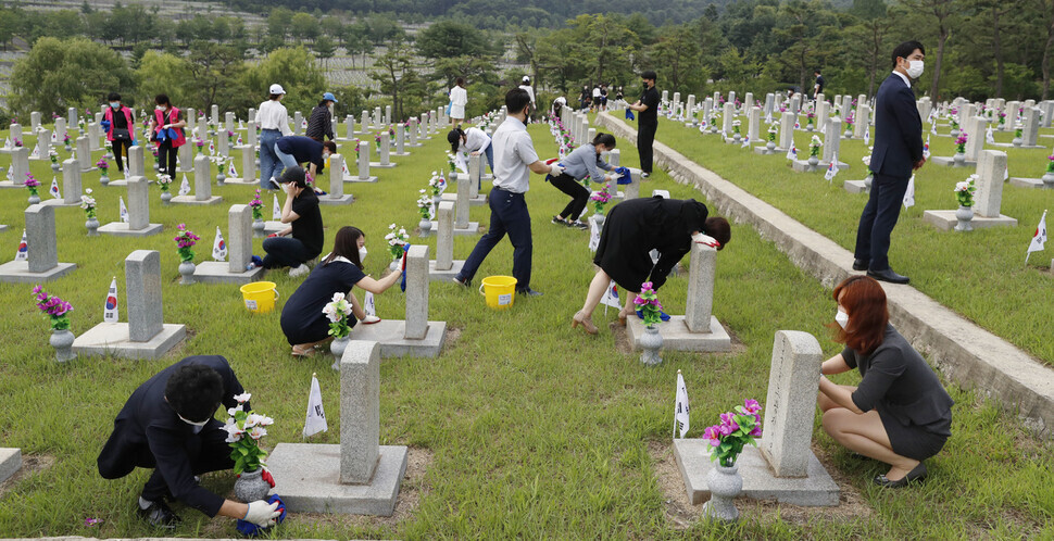 College students involved in a group focusing on North Korea and unification clean gravestones of soldiers killed in the Korean War at the national cemetery in Seoul on Thursday. (Kim Hye-yun/The Hankyoreh)