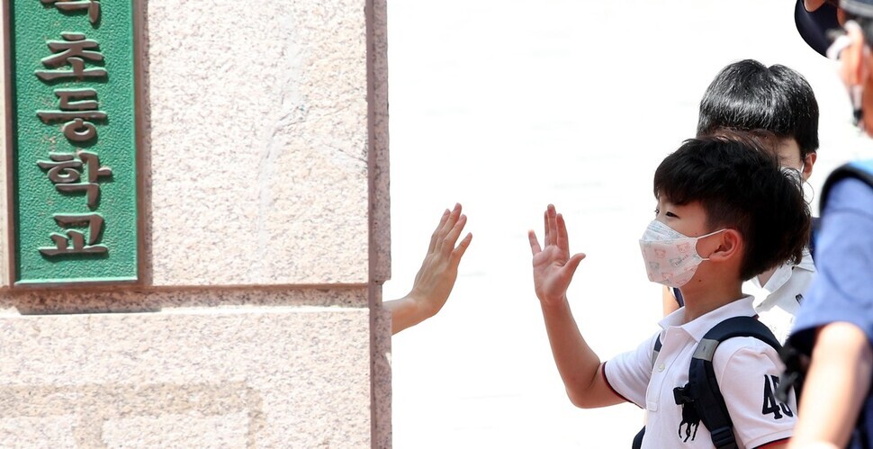 A student at an elementary school in Seoul waves goodbye to his teacher after classes on Aug. 25, as schools in the Greater Seoul region are scheduled to hold classes remotely until Sept. 11. (Kim Bong-gyu, staff photographer)