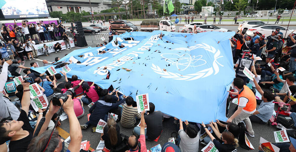 Participants in a national day of action rally against the dumping of radioactive wastewater from the Fukushima nuclear power plant rip up a copy of the IAEA’s comprehensive report on the discharge plan. (Kim Jung-hyo/The Hankyoreh)