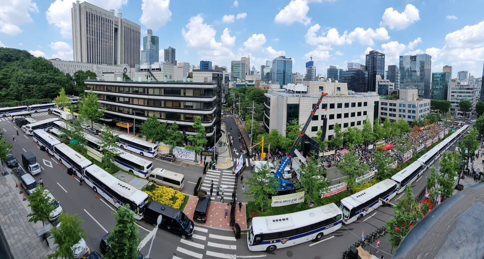윤석열의 구속영장 실질심사가 열린 2025년 7월9일 오후 서울중앙지법 앞 삼거리가 경찰 버스와 바리케이드로 통제된 가운데 지지자들이 들머리에 모여 영장 기각 등을 외치며 집회하고 있다. 윤석열 지지자들의 집회는 전과 견주면 규모가 확연히 줄어들었다.