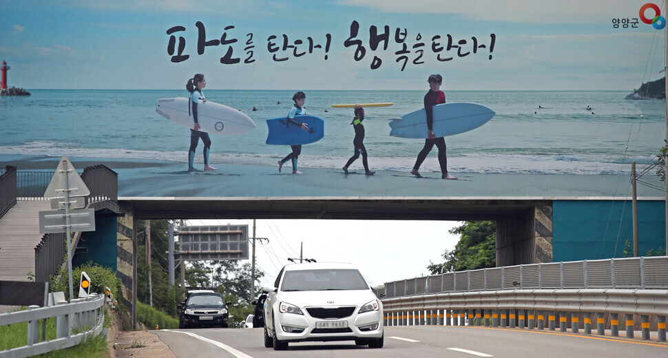 A tourist ad for surfing lines an overpass on the road leading to beaches in Yangyang, Gangwon Province. (Lee Jeong-yong/The Hankyoreh)