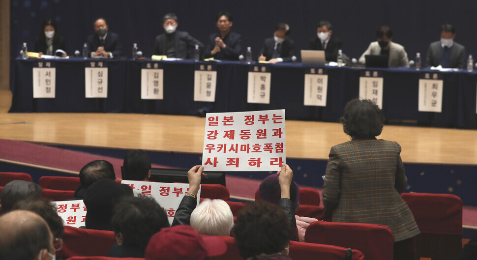 Victims of Japan’s wartime forced labor and their advocates attend a public debate at the National Assembly on Jan. 12, with one holding up a sign that reads “Japanese government: Apologize for forced labor and bombing the Ukishima!” (Kang Chang-kwang/The Hankyoreh)