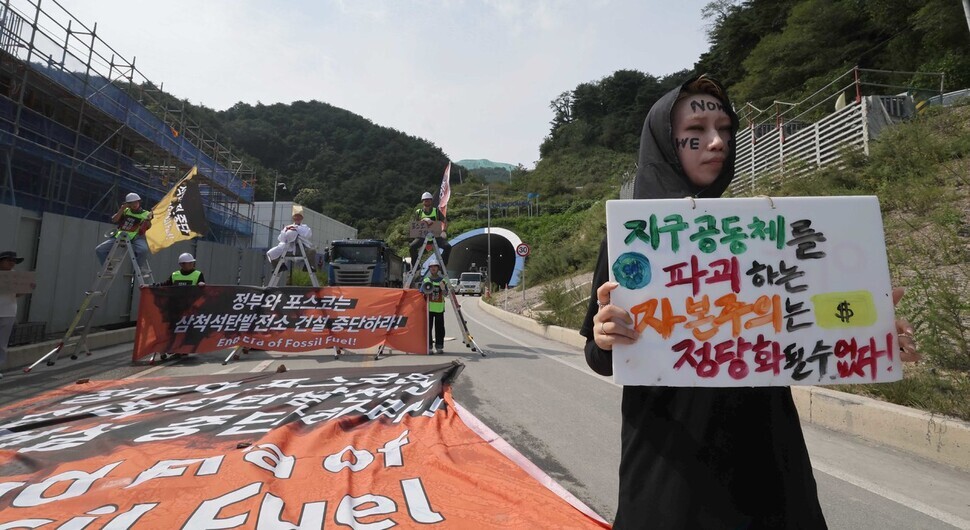 Korean environmental activists occupied a road leading to a coal power station being built by Samcheok Blue Power in Samcheok, Gangwon Province, on Sept. 12. The sign pictured here reads, “Capitalism that destroys the community of Earth cannot be justified!” (Park Jong-shik/The Hankyoreh)