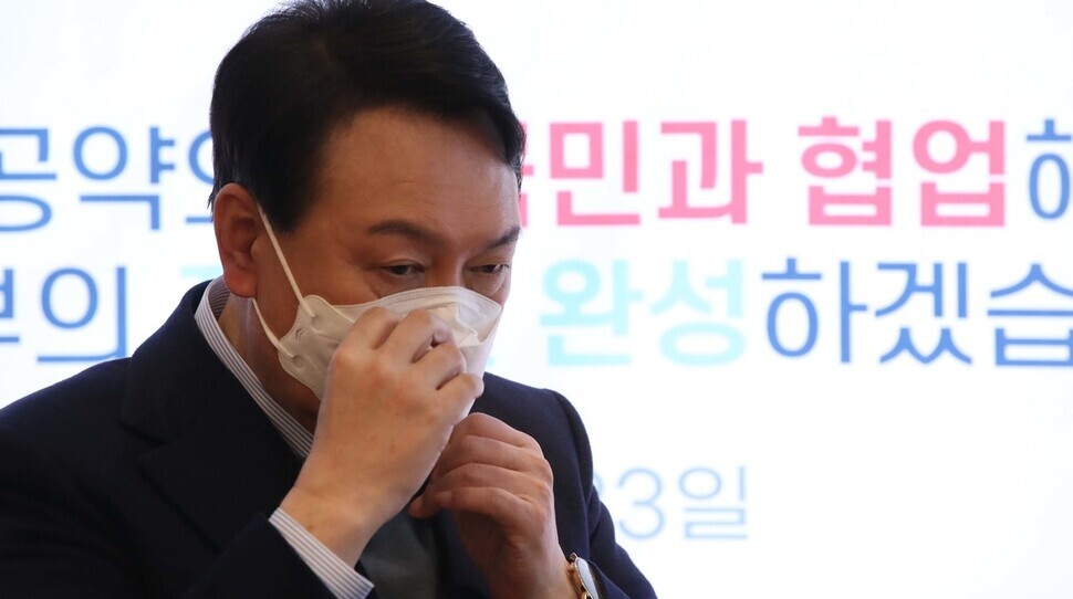 People Power Party presidential nominee Yoon Suk-yeol adjusts his mask while at a campaign event at a cafe in Seoul’s Yeouido neighborhood on Sunday. (pool photo)