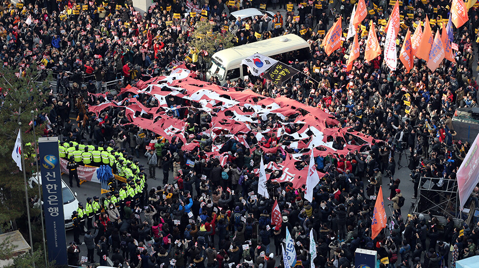 Protesters tear apart a banner with the name of the ruling Saenuri Party during a demonstration in front of the party’s headquarters in Seoul’s Yeouido neighbourhood