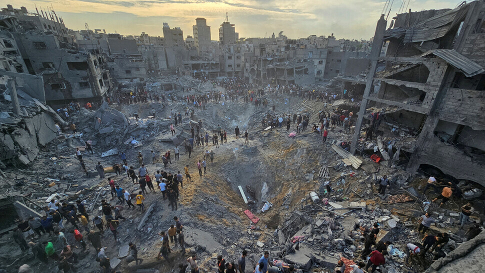 Palestinians stand around a crater left by the impact of an Israeli Defense Force airstrike on the Jabalia refugee camp in Gaza on Oct. 31. The blast killed 50 residents of the camp. (Reuters/Yonhap)