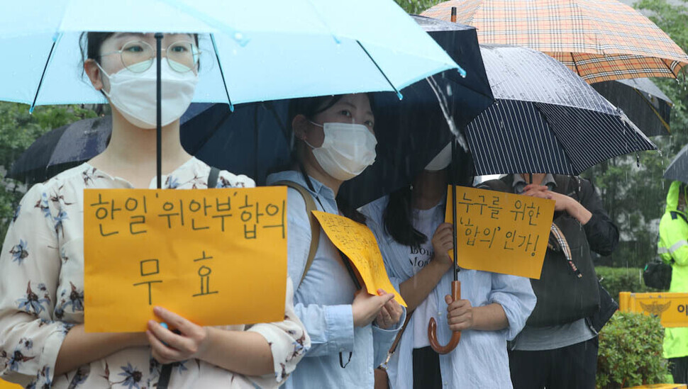 Participants in the 1,550th Wednesday Demonstration calling for the resolution of the issue of wartime sexual slavery by the Japanese military stand in the rain outside the former Japanese Embassy in downtown Seoul on June 29, calling for an apology and compensation from Japan. (Kim Jung-hyo/The Hankyoreh)