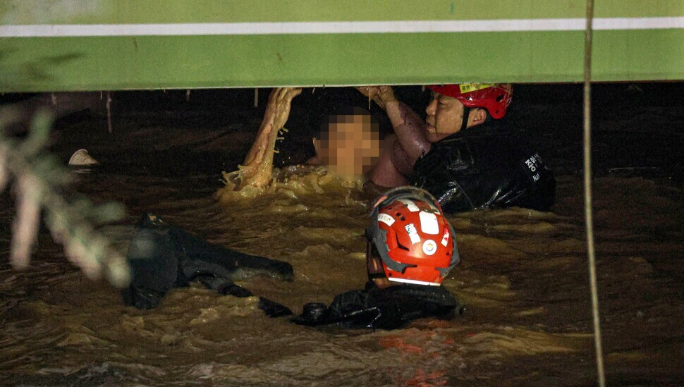 Members of the fire department’s search team guide an individual who was trapped in a flooded apartment basement parking garage in Pohang to safety on Sept. 6. Rain from Typhoon Hinnamnor caused the garage to flood, trapping seven people within it. (Maeil Shinmun)