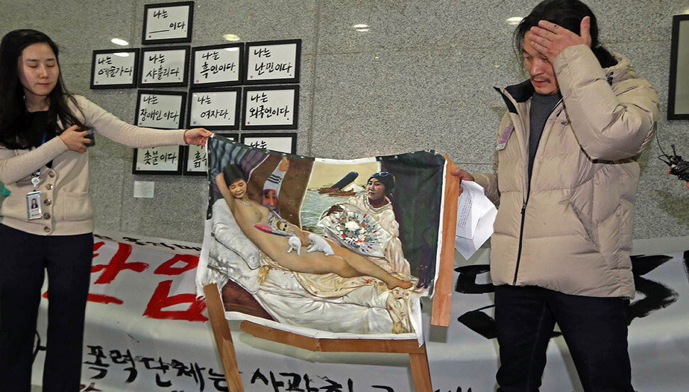 Visitors take photos at an exhibition of satirical art titled “Got