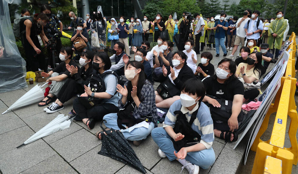 Participants in the 1,550th Wednesday Demonstration calling for the resolution of the issue of wartime sexual slavery by the Japanese military sit in the rain outside the former Japanese Embassy in downtown Seoul on June 29, calling for an apology and compensation from Japan. (Kim Jung-hyo/The Hankyoreh)