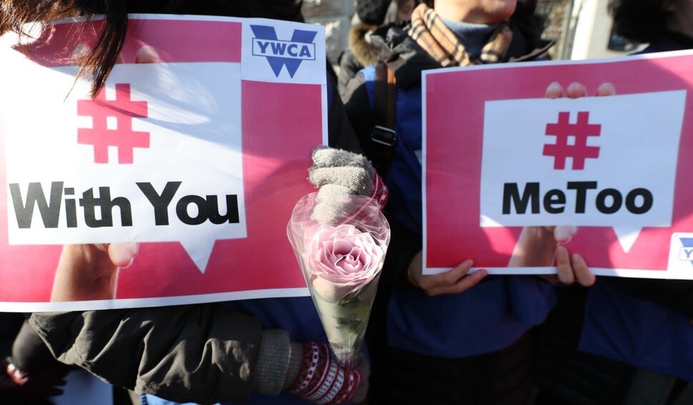 A woman holds a white rose between two signs during a MeToo demonstration in front of the Supreme Prosecutors’ Office in the Seocho district of Seoul on Feb. 1. The white rose is the symbol of the MeToo movement. (by Baek So-ah