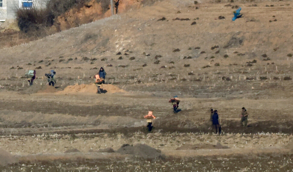 On Feb. 15, one day prior to the birth anniversary of Kim Jong-il, North Koreans in Kaepung County, North Hwanghae Province, can be seen working in the fields. The photo was taken from South Korea’s city of Paju, in Gyeonggi Province. (Yonhap)
