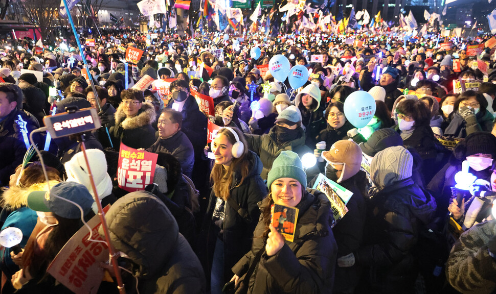 시민과 외국인들이 한데 어울려 2024년 12월28일 밤 서울 광화문 앞 사직로 거리를 행진하고 있다.