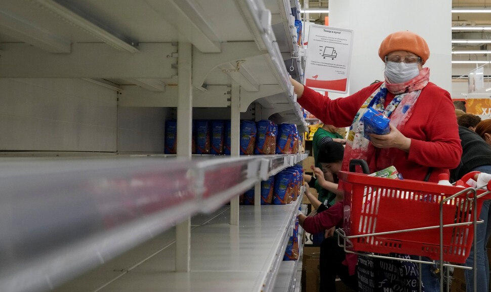 2020년 3월 러시아 모스크바의 한 슈퍼마켓에서 코로나19 방역을 위해 마스크를 쓴 시민이 곡물과 밀가루 선반이 텅 빈 가운데 그 옆에서 다른 먹거리를 살펴보고 있다. REUTERS 연합뉴스