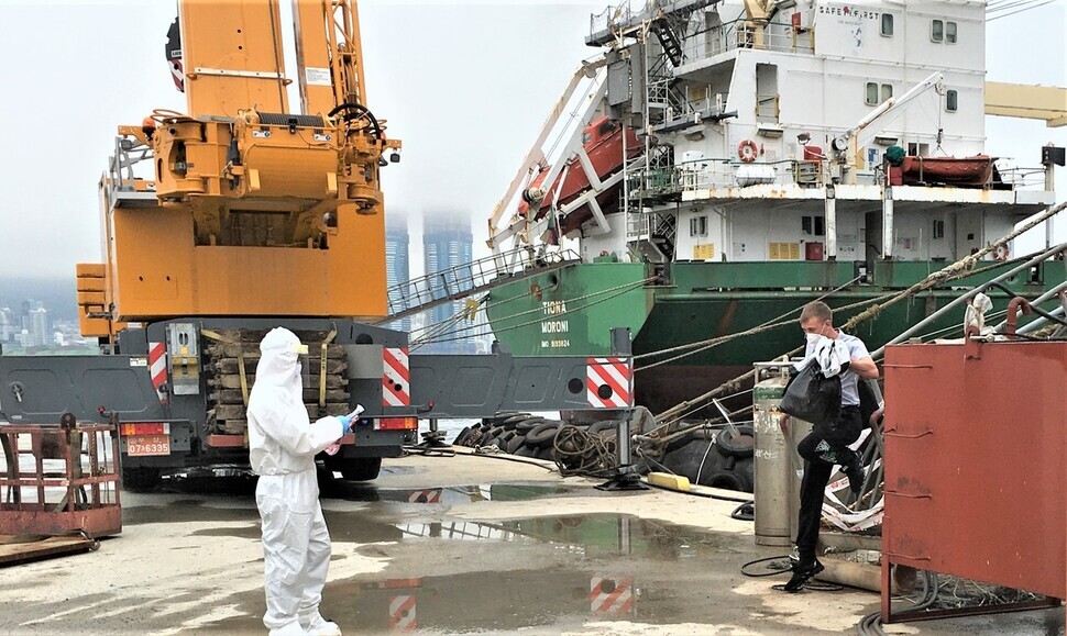 A crew member from a Russian ship docked at the Port of Busan disembarks to be transported to a medical facility. (Yonhap News)