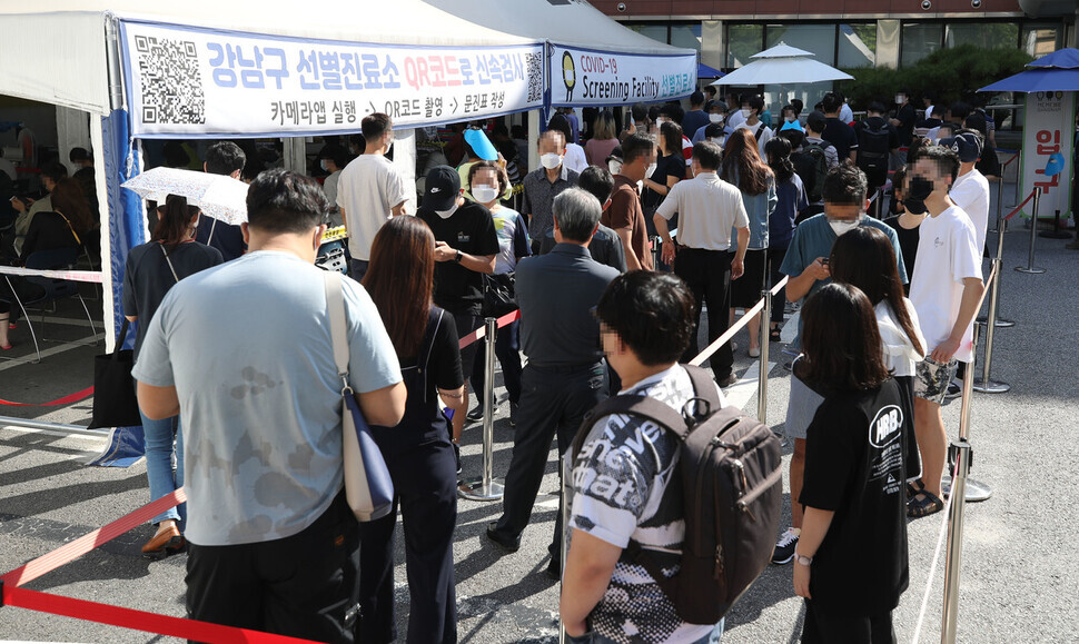 People wait in line to get tested for COVID-19 at a temporary screening center in Seoul on Friday. (Yonhap News)