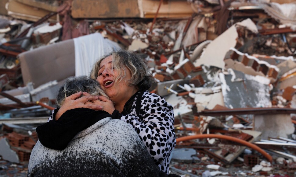 강진 발생 다음날인 7일(현지시간) 지진으로 붕괴한 튀르키예 하타이의 건물 잔해 앞에서 두 사람이 서로 끌어안고 있다. 하타이 로이터=연합뉴스